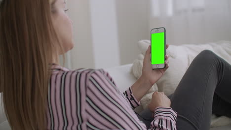 Junge-Frau-Nutzt-App-Für-Videoanrufe-In-Einem-Modernen-Smartphone-Mit-Grünem-Bildschirm-Für-Chroma-Key-Technologie,-Die-über-Das-Internet-Chattet